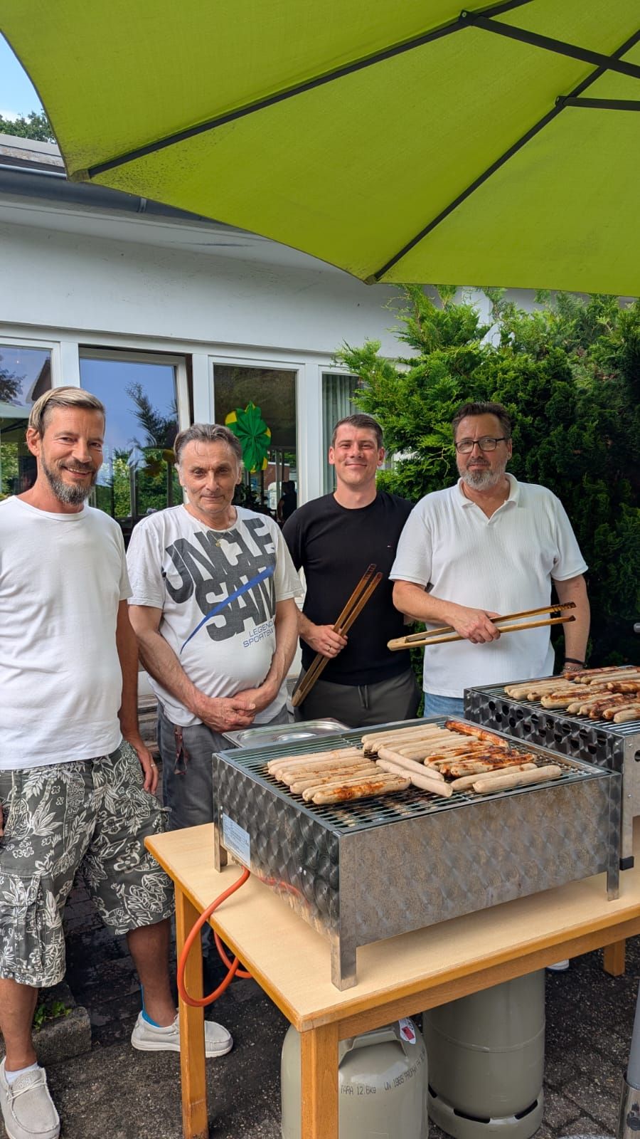 Vier Mitarbeiter grillen Würstchen beim Sommerfest 2026 im Lambertistift Oldenburg.