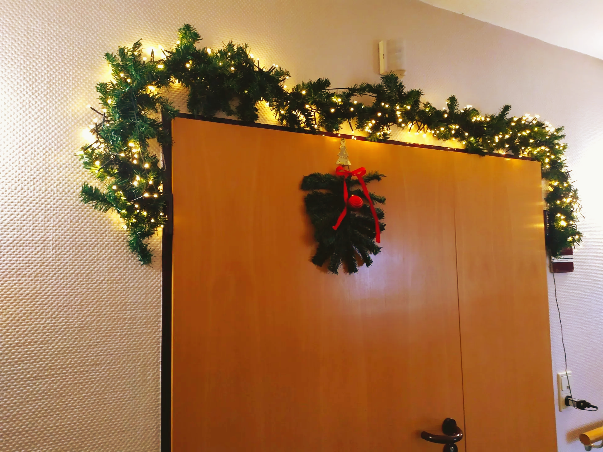 Tür mit Tannengirlande und Lichterkette als Weihnachtsdekoration im Lambertistift.