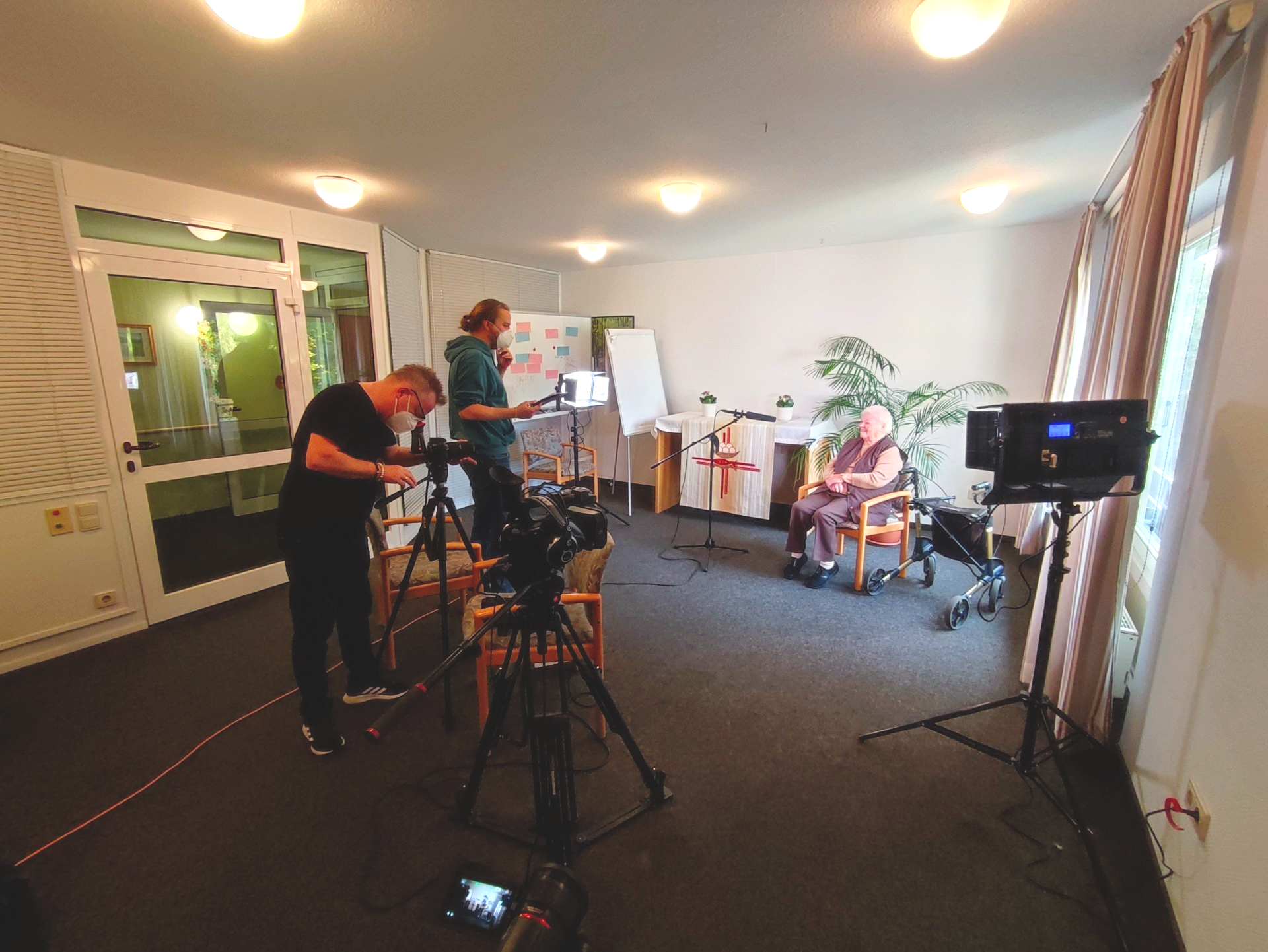 Filmteam bereitet Dreharbeiten mit Bewohnerin für ein Filmprojekt vor.