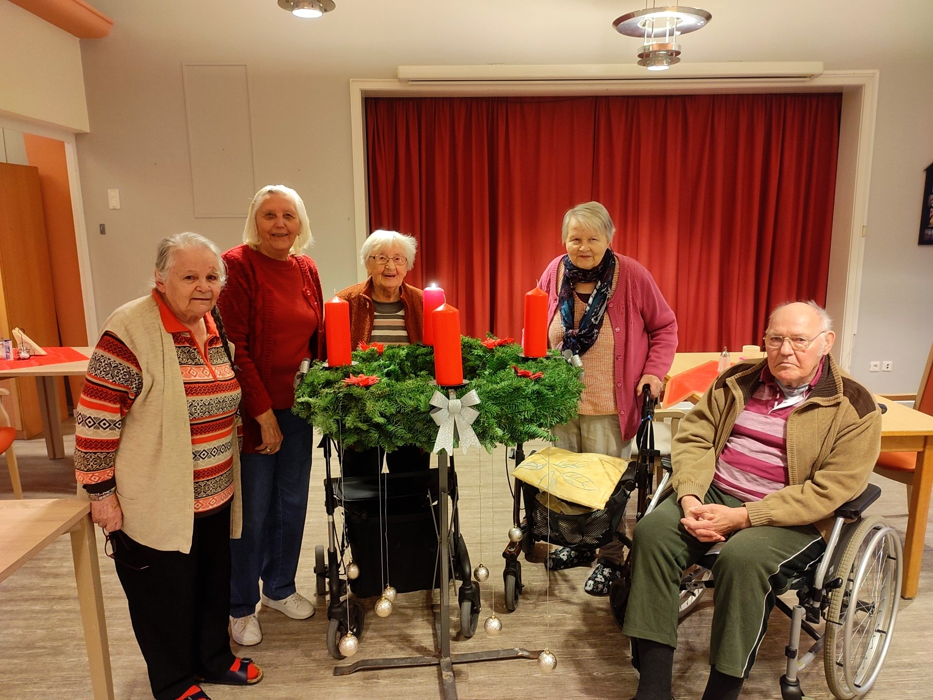Bewohnerinnen und Bewohner mit Adventskranz im Speisesaal.