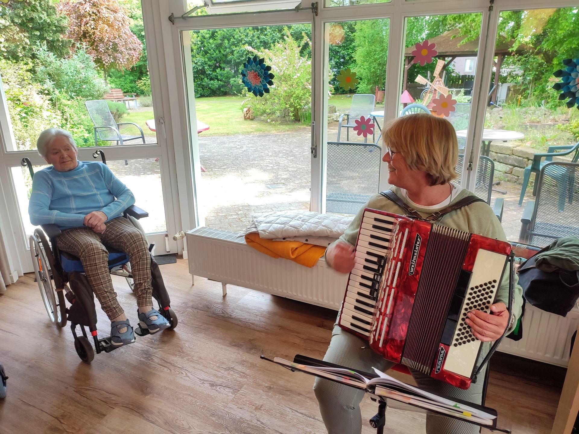 Frau Munzel spielt Akkordeon für Bewohner im Gemeinschaftsraum.