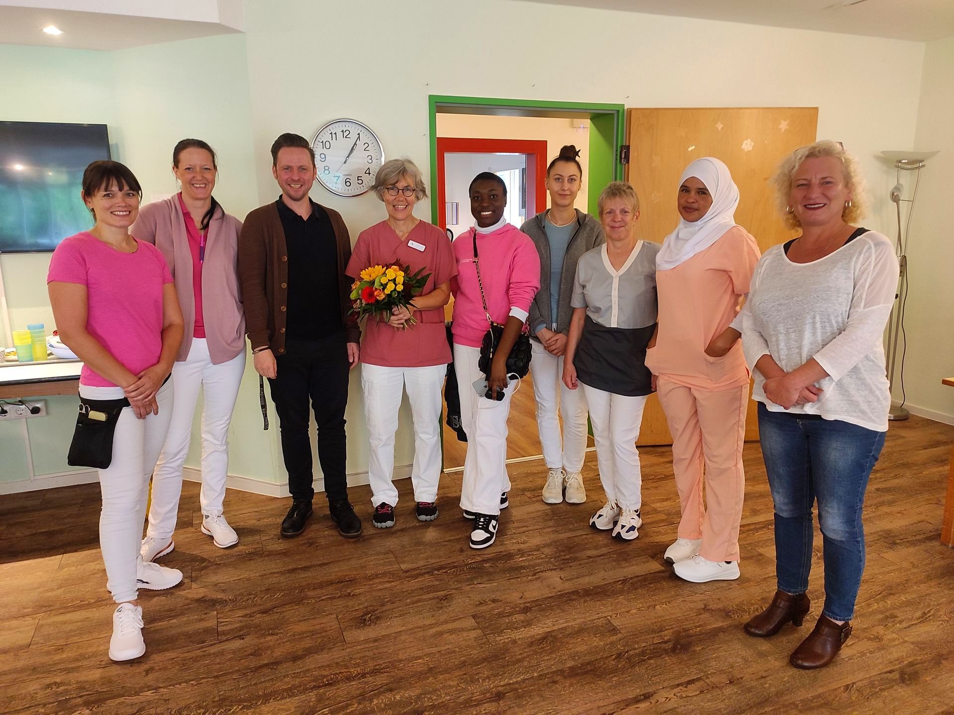 Mitarbeitende des Lambertistifts stehen zusammen, Claudia Jacob hält einen Blumenstrauß bei ihrer Vorstellung als neue WBL.