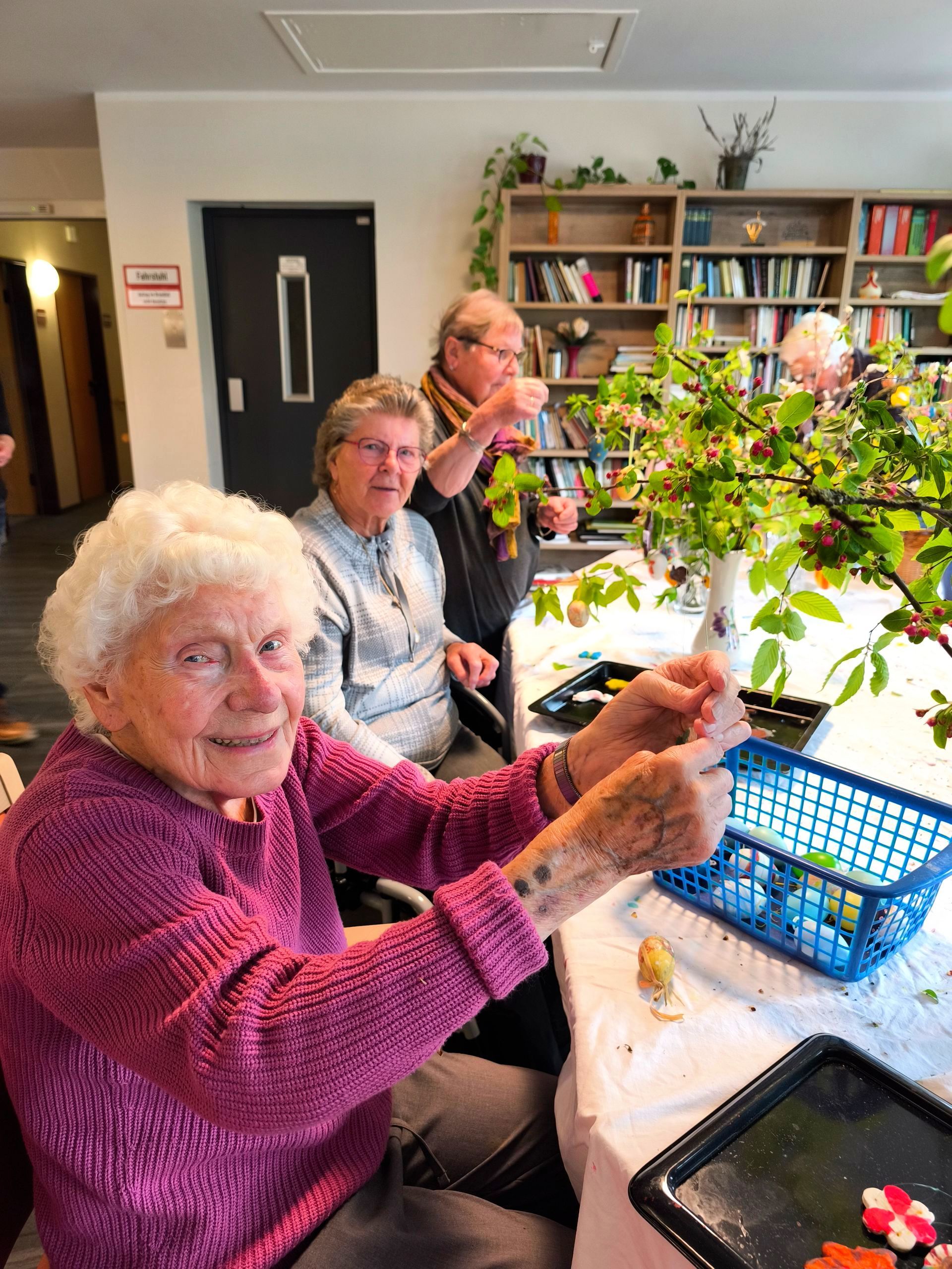 Mehrere Bewohnerinnen sitzen am Tisch und basteln gemeinsam mit Zweigen und Frühlingsblüten