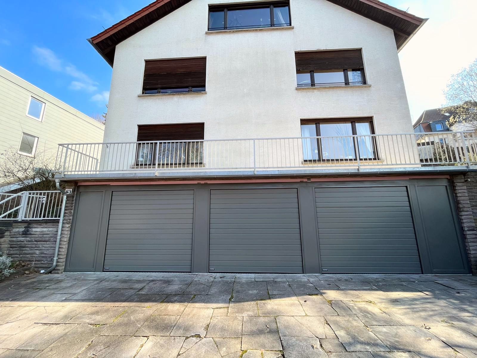 weinor_Markise_LED_neu_Saarland_Rolladen_Kessler komplette Erdgeschoss-Fassade aus drei Garagen-Sectionaltore in grau nebeneinander, dazwischen Aluverkleidungen.