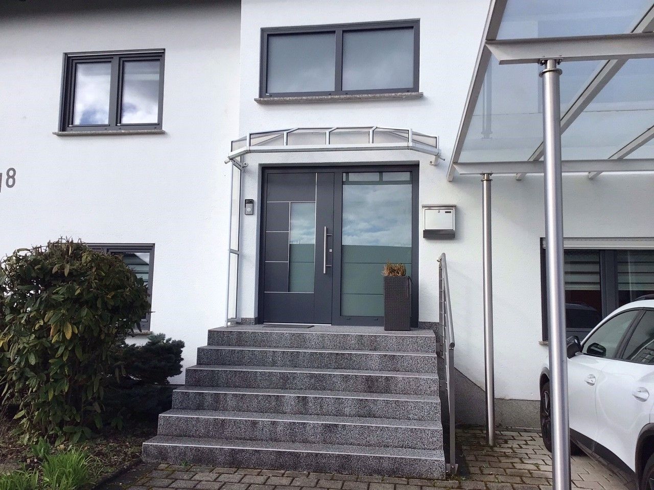 Alu-Haustuer_neu_Saarland_Rolladen_Kessler anthrazitfarbene Haustuer mit Seitenteil und Milchglas. Design mit waagerechten Edelstahl-Applikationen.