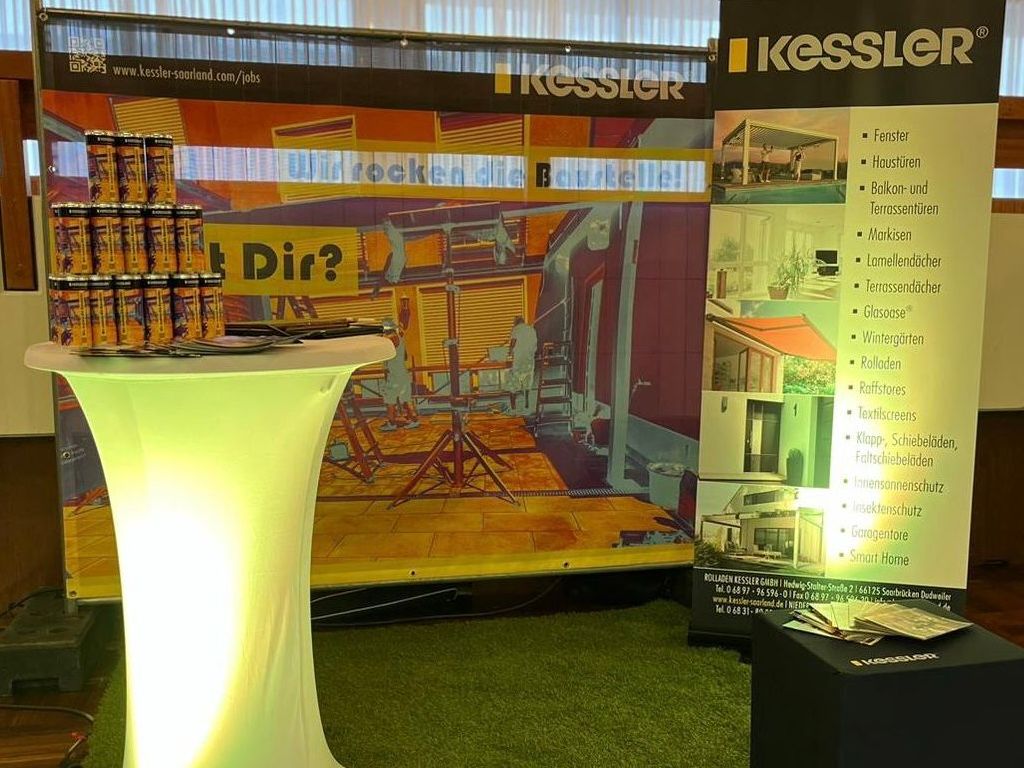 Im Hintergrund steht ein Banner mit einem bunten Thermografiebild einer Baustelle von Rolladen Kessler. Es hat den Slogan 