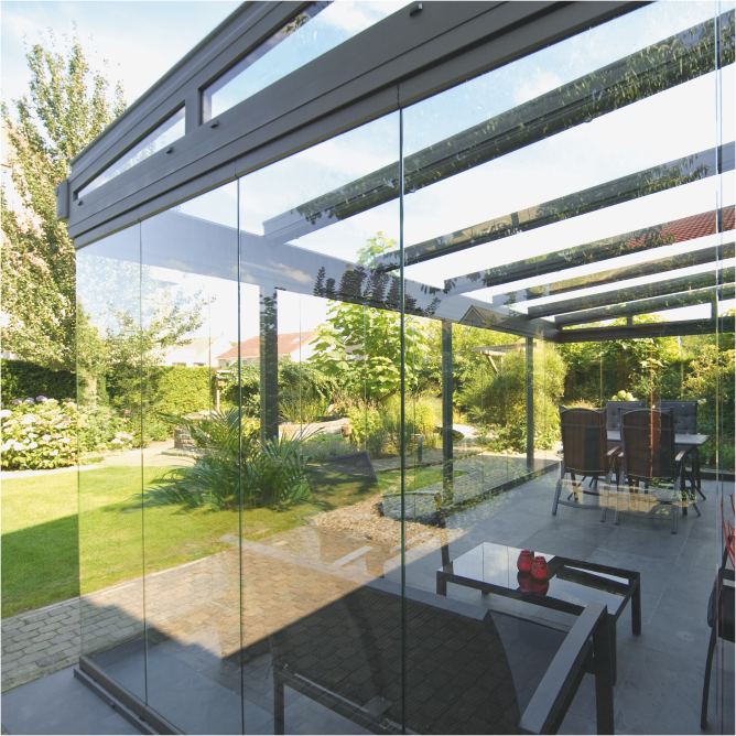 Eine Glasüberdachung die mit Ganzglas-Schiebewänden von weinor zu einem Kalt-Wintergarten oder einer sog. Glasoase ausgebaut wurde. Die Perspektive zeigt wie transparent man durch die Ganzglas-Schiebewände den grünen Garten sieht.