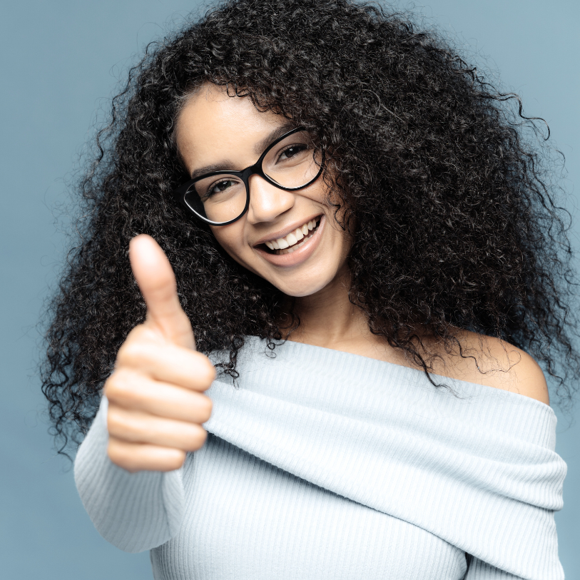 Junge Frau trägt eine gut sitzende optische Brille und zeigt dabei Daumen hoch.