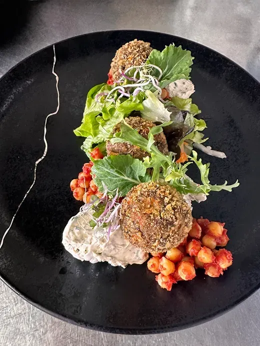 Elegant angerichteter Salat mit Krustentieren, Beeren und knusprigen Komponenten auf schwarzem Teller – Schlosscafé Teningen