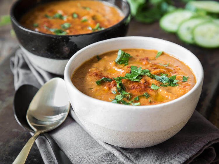 Gesunde Ernährung Zwei Suppenschalen gefüllt mit roter Linsensuppe, dekoriert mit Petersilie. Dazu zwei Suppenlöffel.
