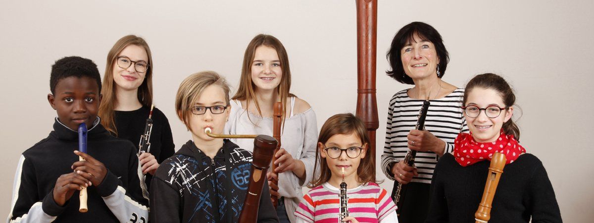 Eine Gruppe von Schülern und eine Leherin mit unterschiedlichen Holzblasinstrumenten.