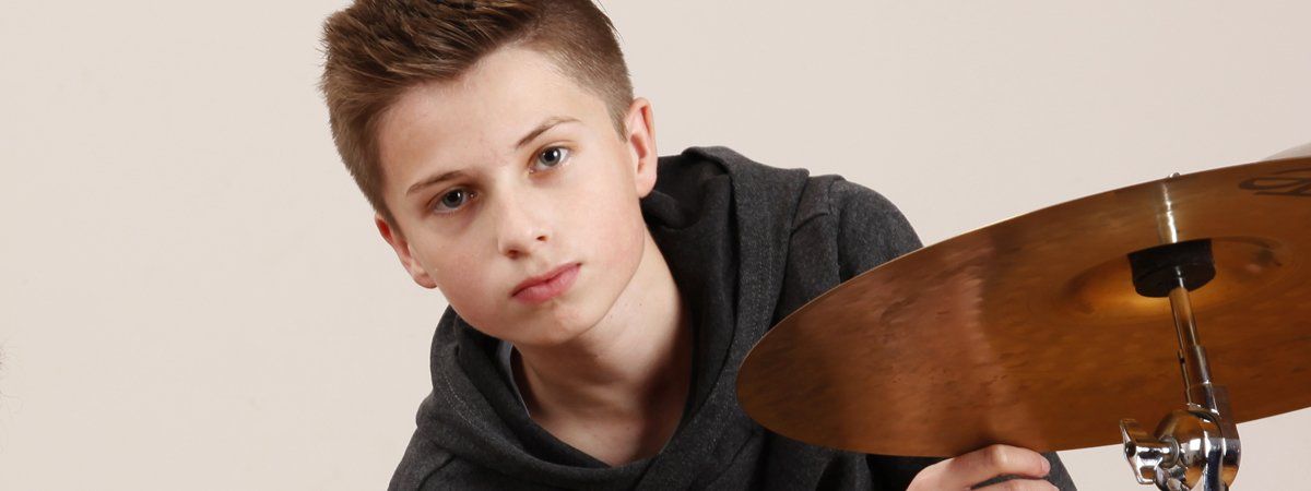 Junge hinter dem Schlagzeug sitzend.