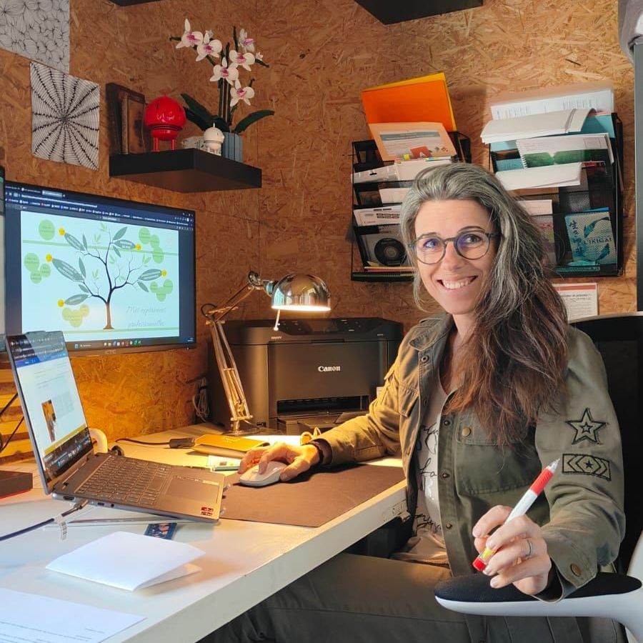 Séverine, la dirigeante de PEPS, sourire aux lèvres, est assise à son bureau où elle travaille.