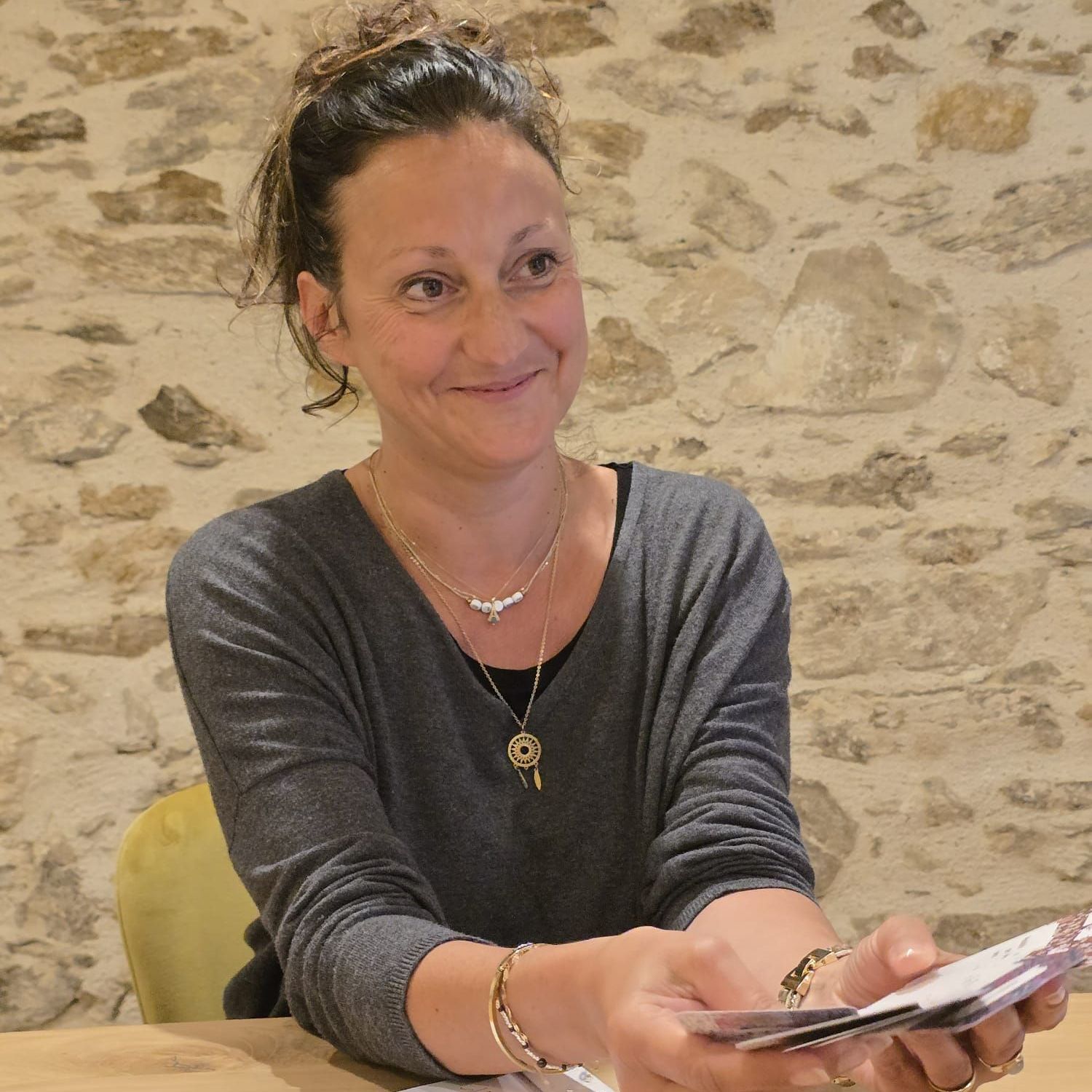 Sandrine souris et est assise avec son PC portable, elle travaille