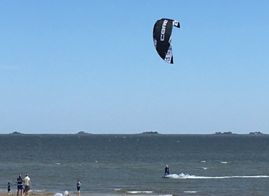 Ob Kiten oder Sonnenbaden – die perfekte Lage der Ferienwohnungen verbindet sportliche Abenteuer und Entspannung am Strand. Kitesurfer über dem Meer vor Föhrs Küste – Nordsee-Aktivurlaub in Ferienwohnungen Haus Matthäus