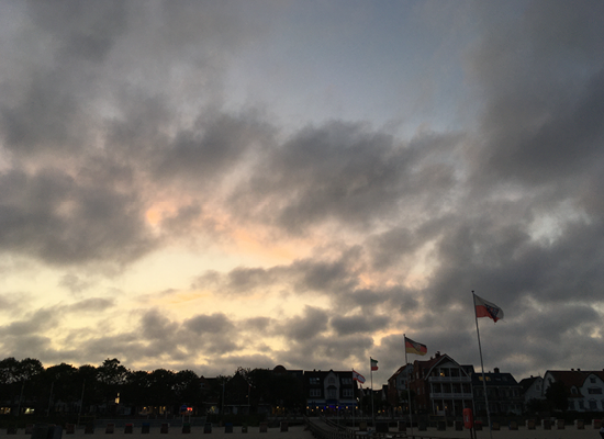 Besondere Abendstimmung mit wildem Flair in Wyk – genießen Sie unvergessliche Momente nahe Ihrem Ferienzuhause. Wyk-Silhouette mit wehenden Flaggen im Sonnenuntergang auf Föhr – eine der vielen schönen Stimmungen an der Nordsee.
