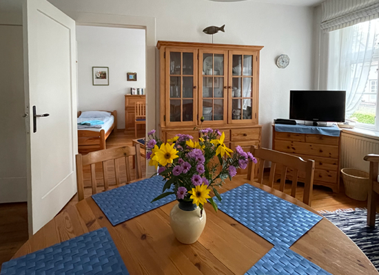 Haus Matthäus FW 1 (EG). Esstisch mit hübschen Blumen, Vitrine, TV. Verbindungstür in 1. Schlafzimmer.