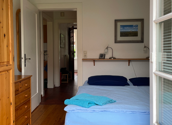 Haus Matthäus Ferienwohnung 1 (EG). Terrassentür Schlafzimmer mit Doppelbett. Angrenzender Flur zum Wohnungseingang.
