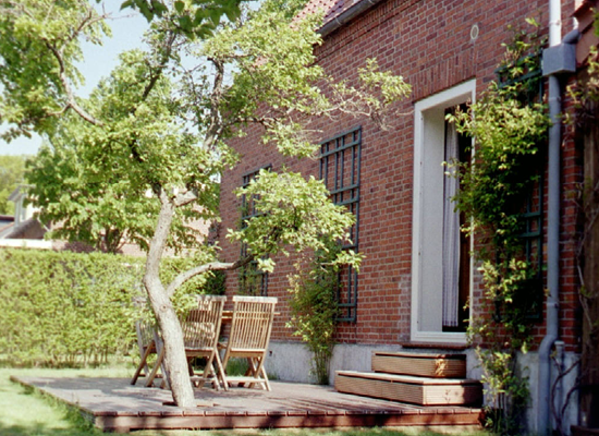 Haus Matthäus Ferienwohnung 1 (EG). Über Holzstufen zur offenen Holzterrasse mit Gartenmöbeln. Uriger Baum.