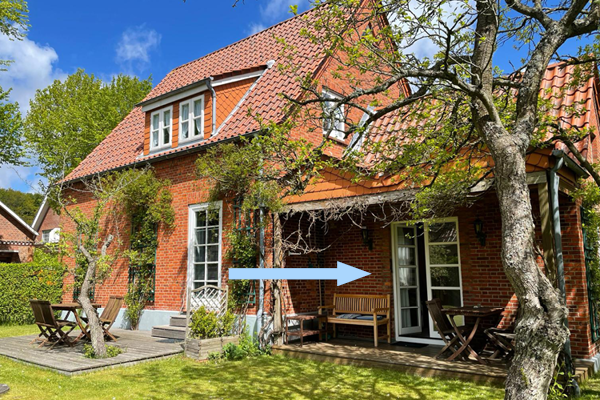 Haus Matthäus Wyk auf Föhr. FeWo 3 Anbau. Rückseite offene Terrassentür, Wohnzimmer. Terrasse überdacht, mit Gartenmöbeln.