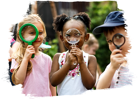 Kinder liegen auf dem Bauch auf einer Wiese mit ausgestreckten Armen und Fingern