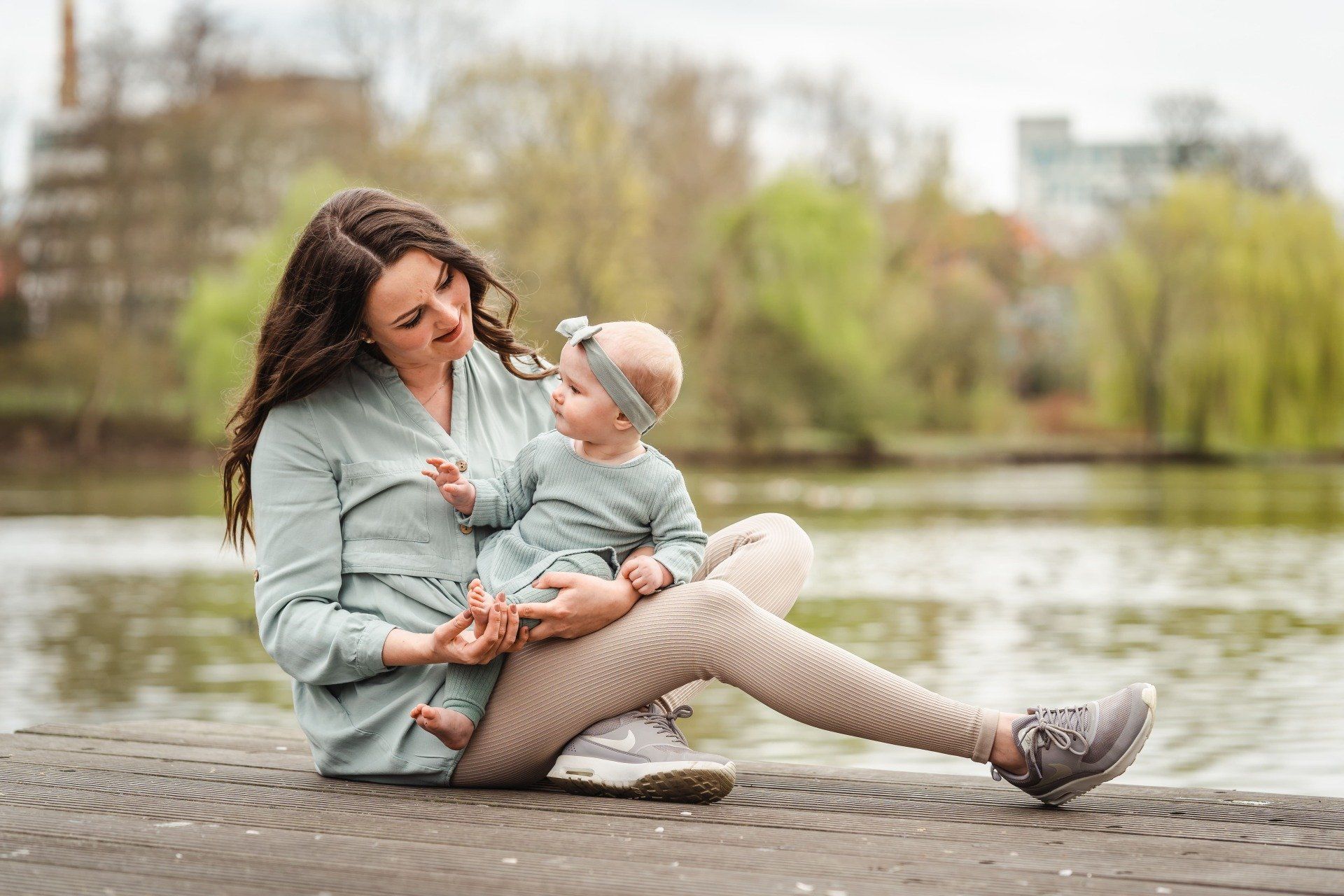 Mutter sitzt mit Tochter auf einem Steg am See