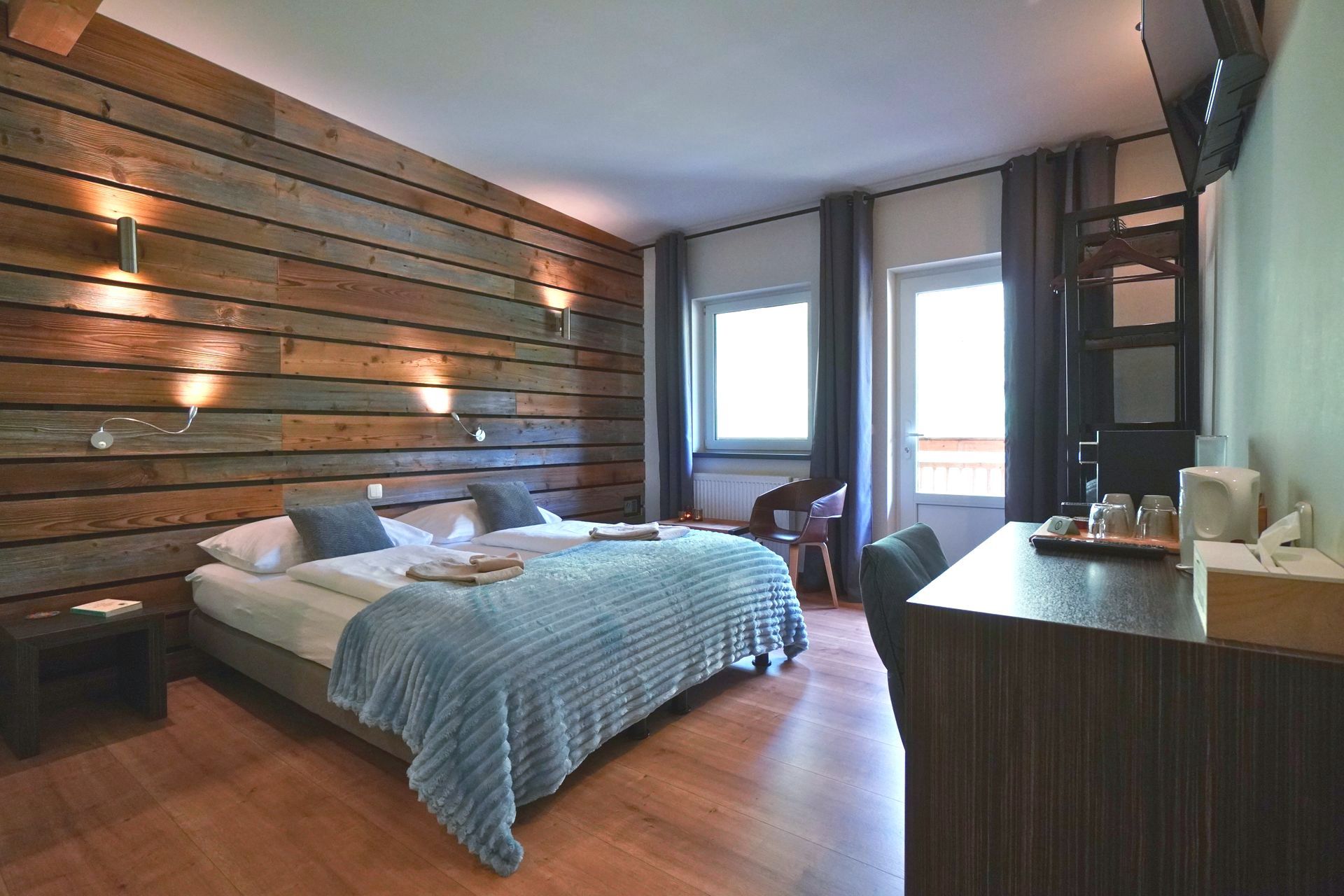 Mehr Zimmer ansehen Room No. 9 | Fallbach, view into the room of the double bed, bedside table, desk, open wardrobe, balcony door