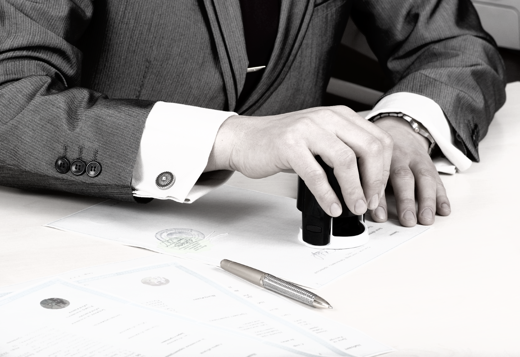 Abogado poniendo un sello en unos papeles de un divorcio internacional, firma varios papeles en varios idiomas.