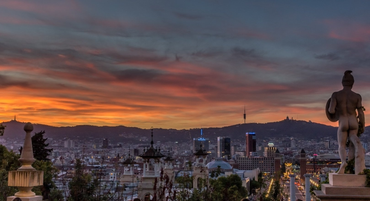 Foto panorámica de Barcelona desde Montjuic, aparece a la derecha una escultura de influencia griega.