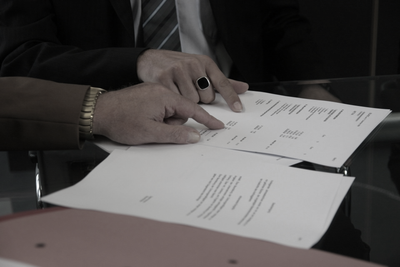 Abogados e familia de dos clientes reunidos y revisando la sentencia de divorcio de sus clientes, intentando llegar a un acuerdo.