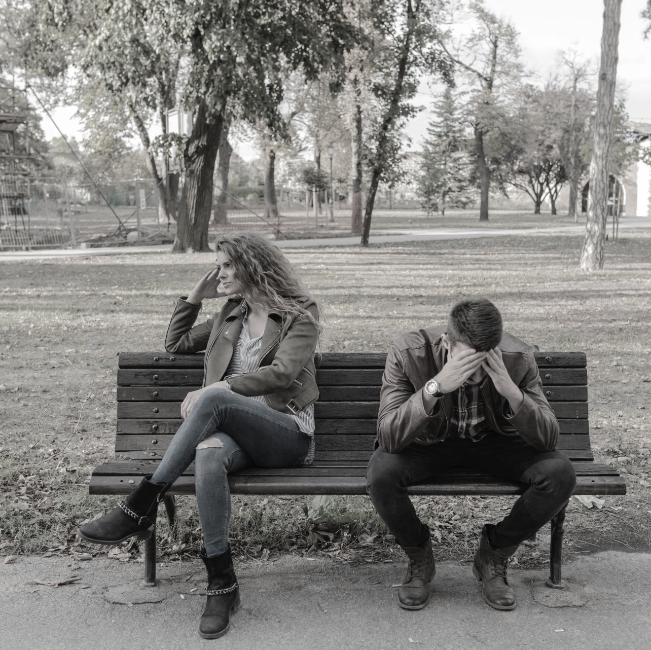 Un hombre y una mujer que son pareja tristes en el banco de un parque, acaban de tener un discusión que no ha ido bien y están llorando.