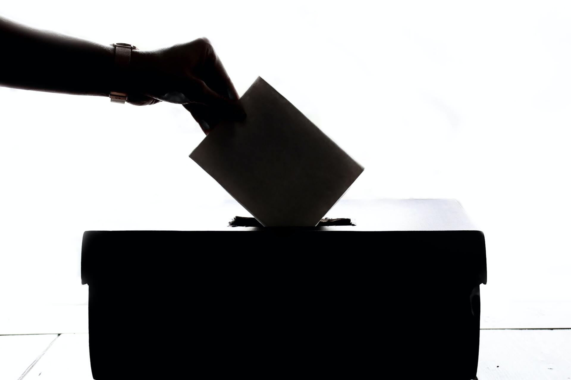 Mano introduciendo un voto en una urna electoral