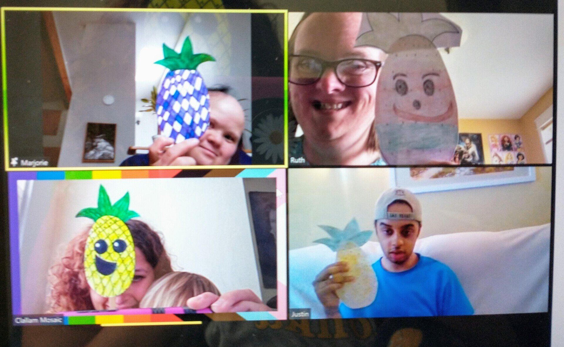 A group of four people showing off the art they createed during a Zoom seesion.