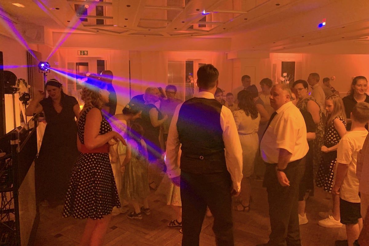 Eine Party-Szene mit beleuchteter Tanzfläche und tanzenden Menschen