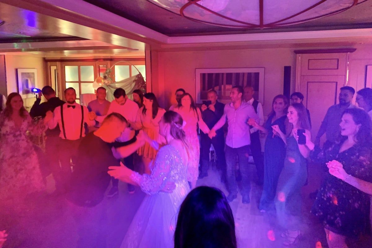 Eine Party-Szene mit lila Beleuchtung und tanzenden Menschen