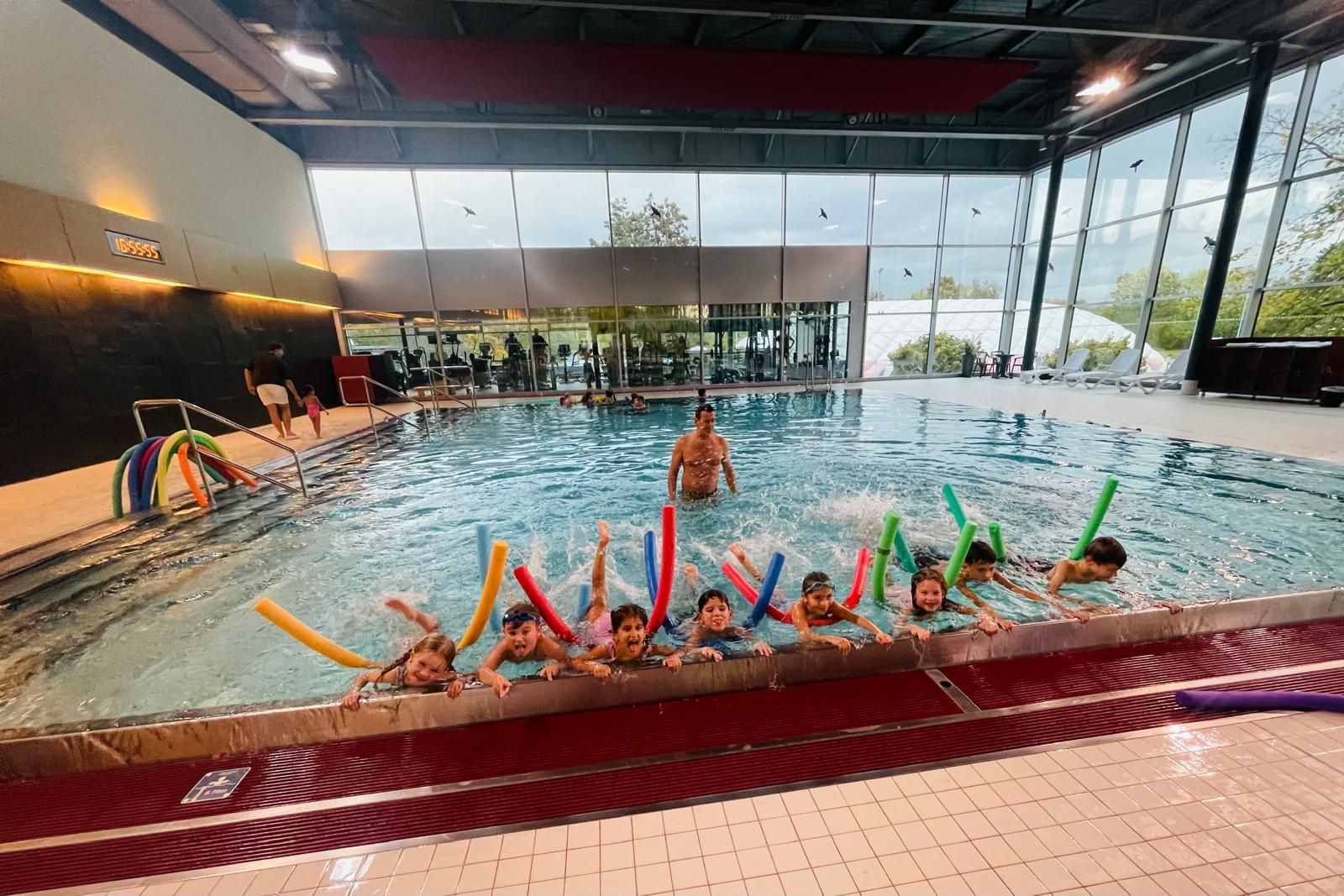Akueller Kurs in der Schwimmschule, Schwimmtrainer mit Kindern im Wasser