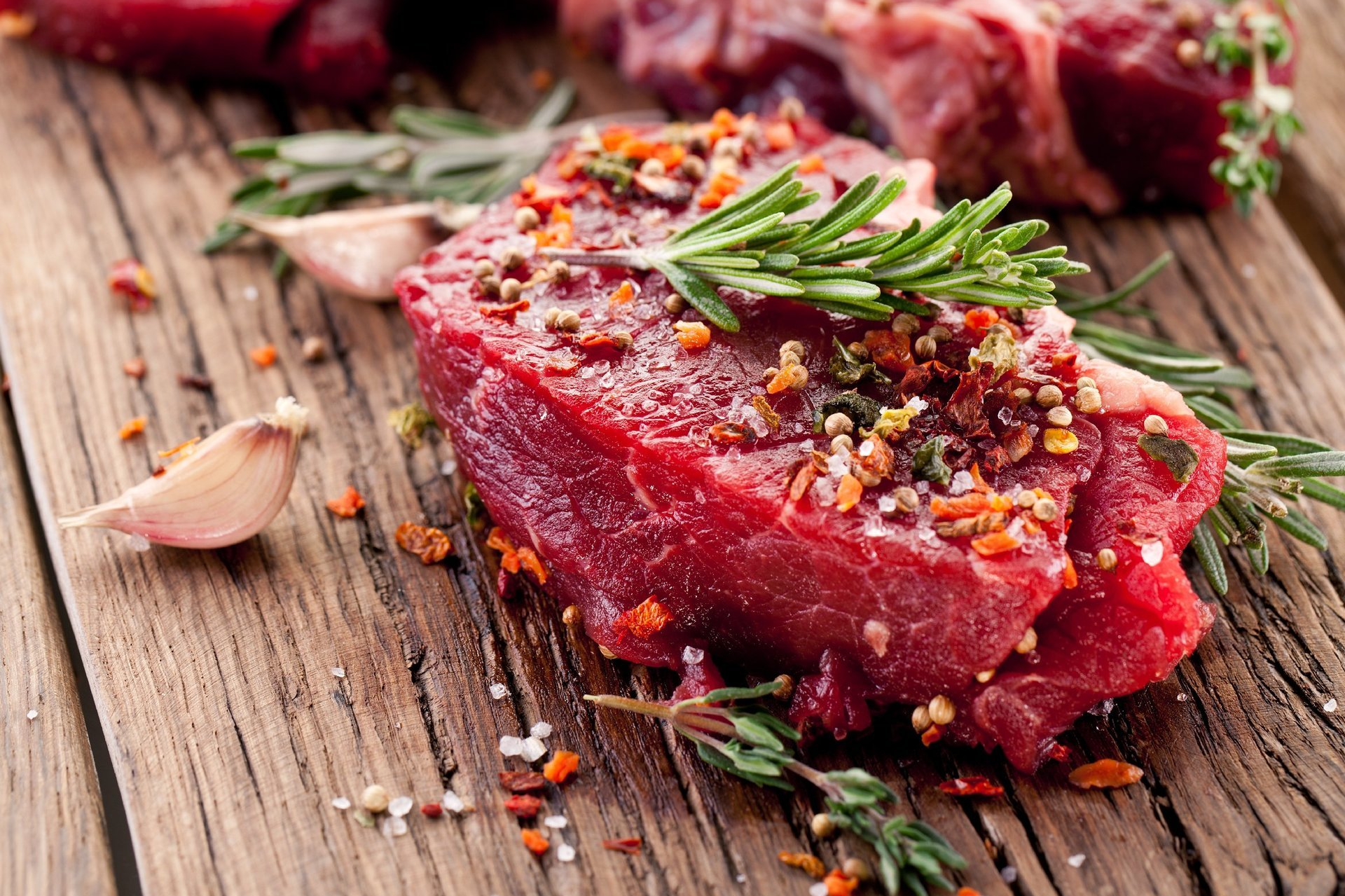 Steakfleisch mit Rosmarinzweig auf Holzbrett Steakfleisch mit Rosmarinzweig auf Holzbrett