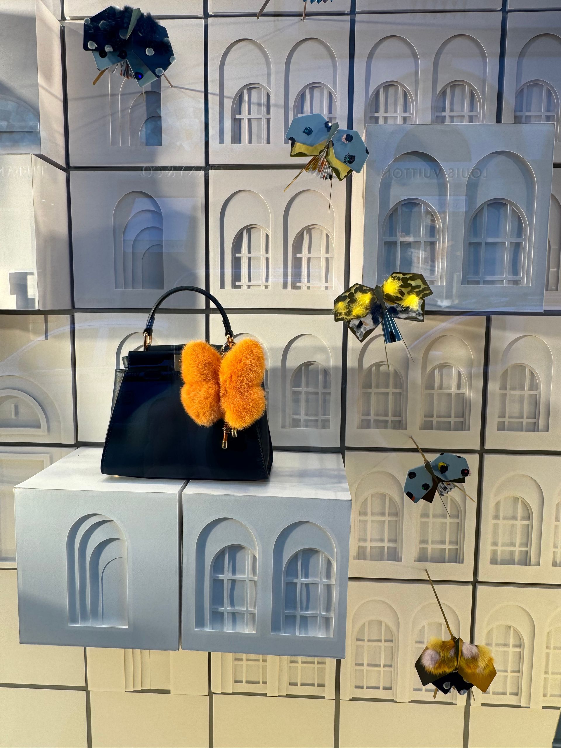 Borsa nera firmata con portachiave arancione a forma di farfalla