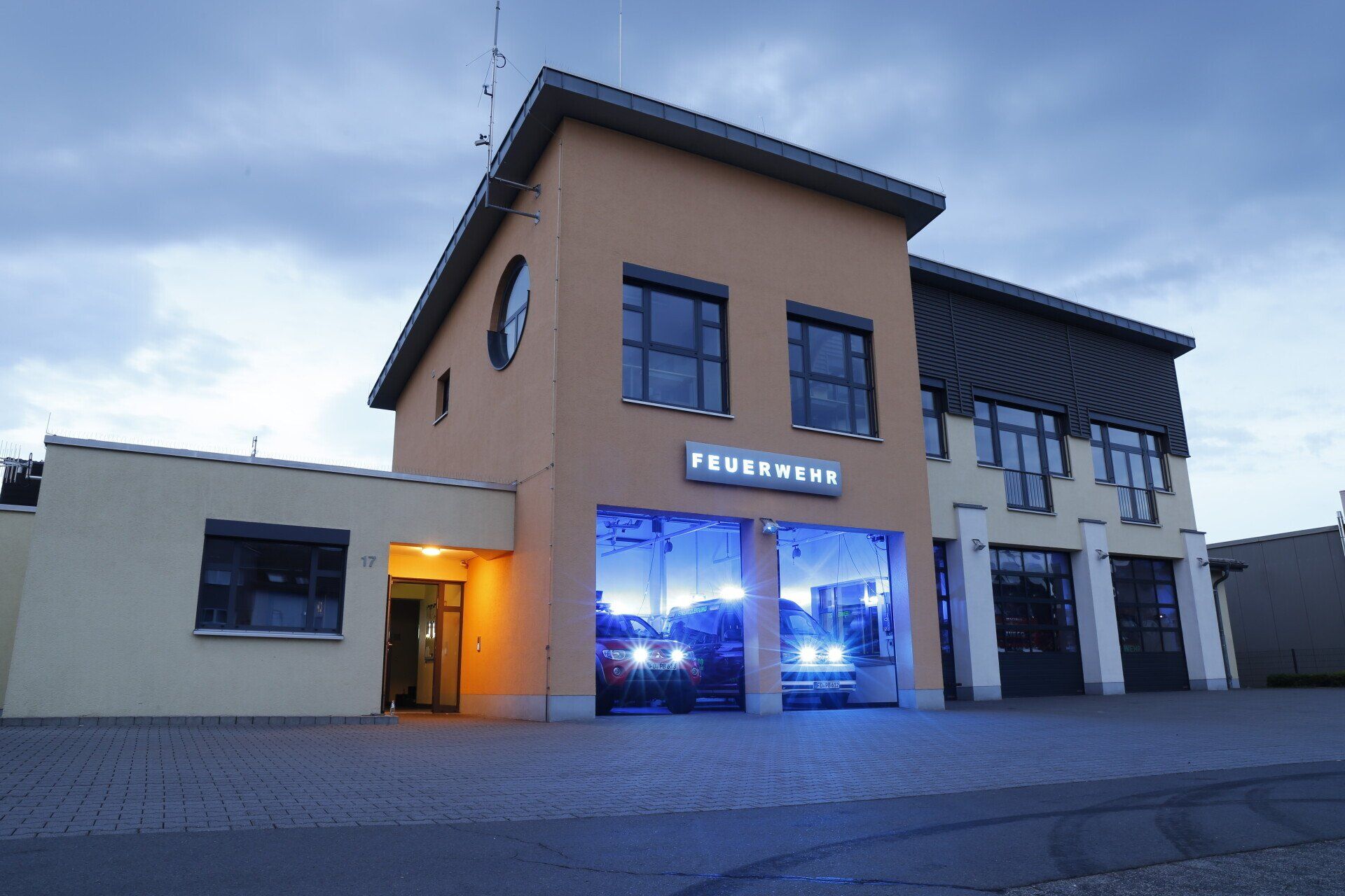 (Symbolbild) Feuerwehrgerätehaus mit ausrückenden Fahrzeugen