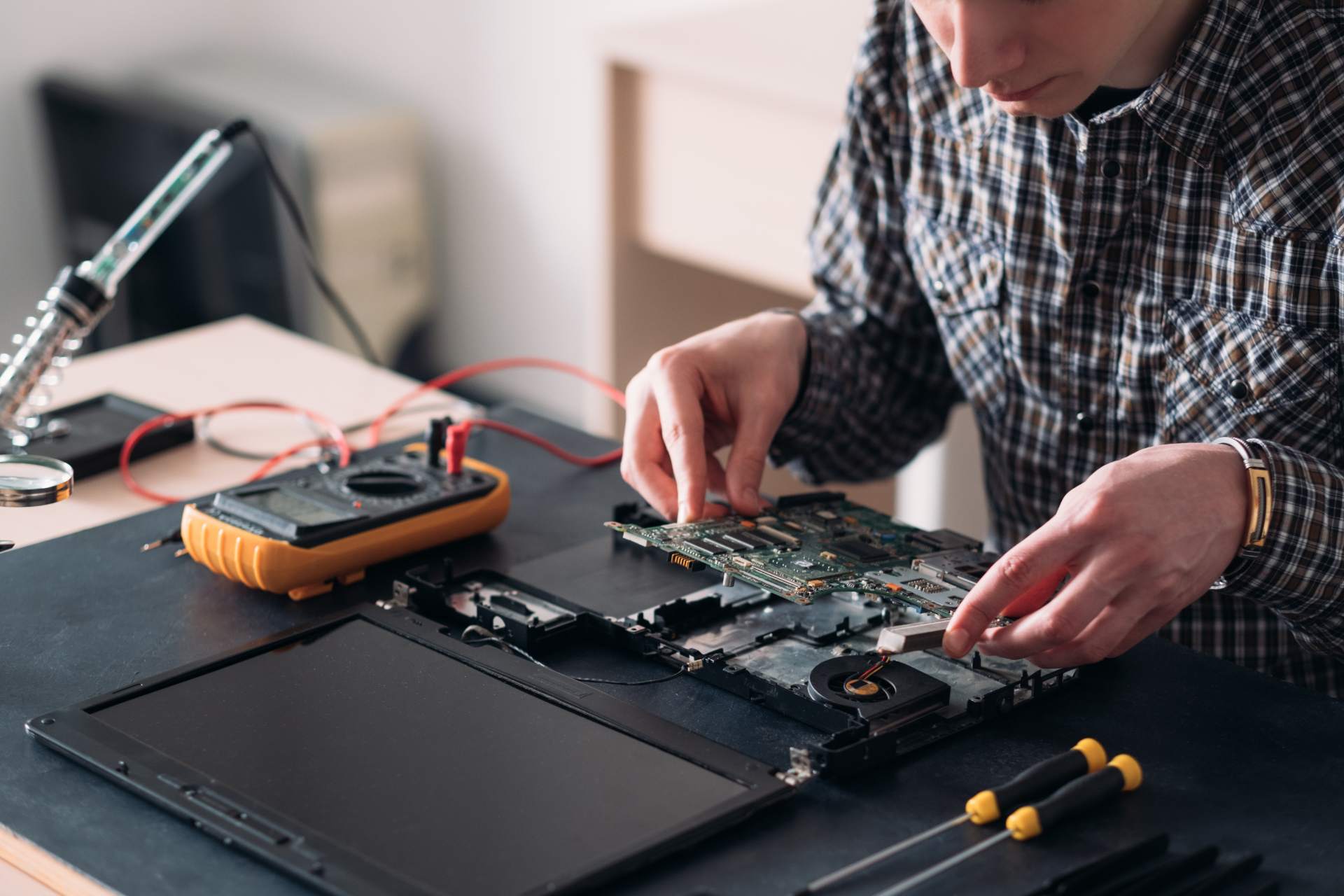 Technician performing component-level repair on Mac logic board to resolve boot issues