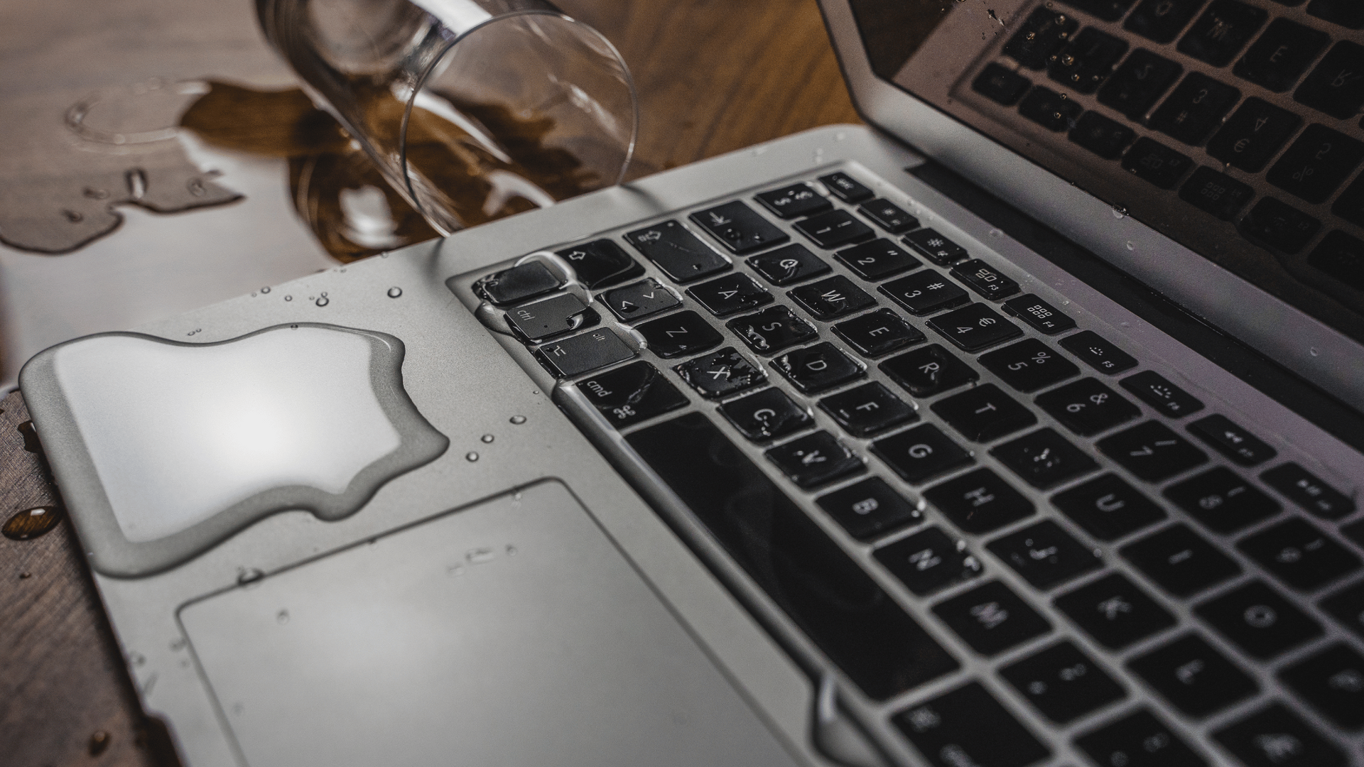 Water-damaged MacBook with visible liquid spill on keyboard