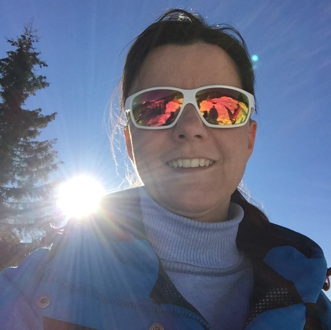 Frau mit Sportbrille im Gegenlicht mit Skijacke