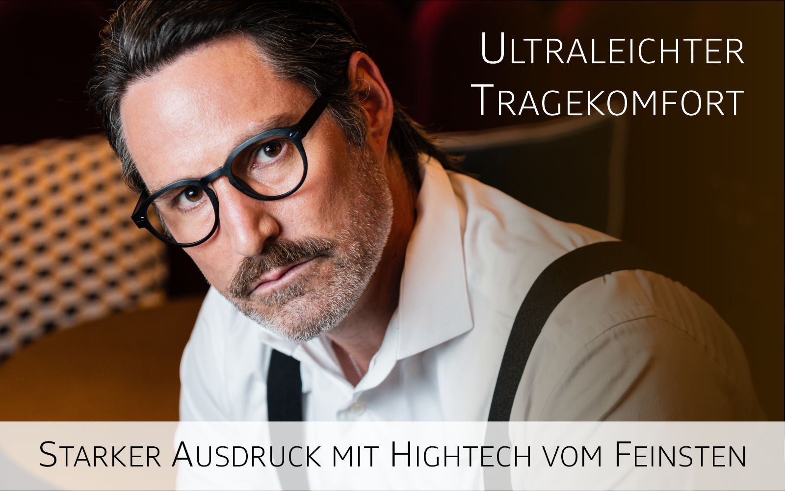 Dunkelhaariger Mann mit 3 Tagebart und schwarzer Imago Ultralight Brille schaut den Betrachter an. Text Ultraleichter Tragekomfort, Saterker Ausdruck mit Heichtech vom Feinsten.