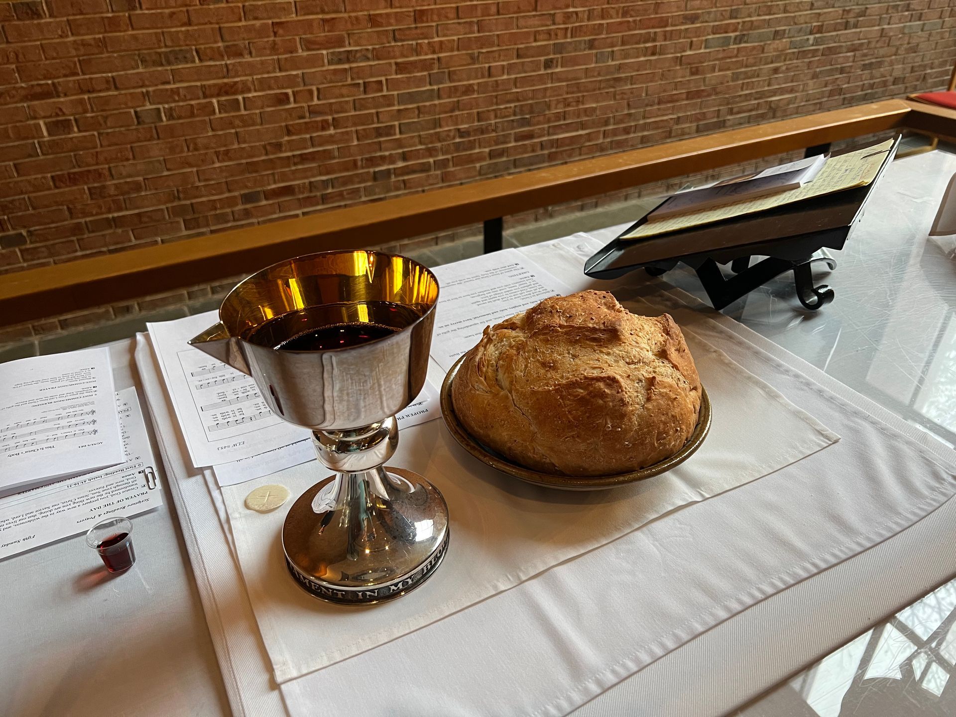 common wine in a silver chalice along side an homemade loaf of bread on the altar ready to be served as communion.