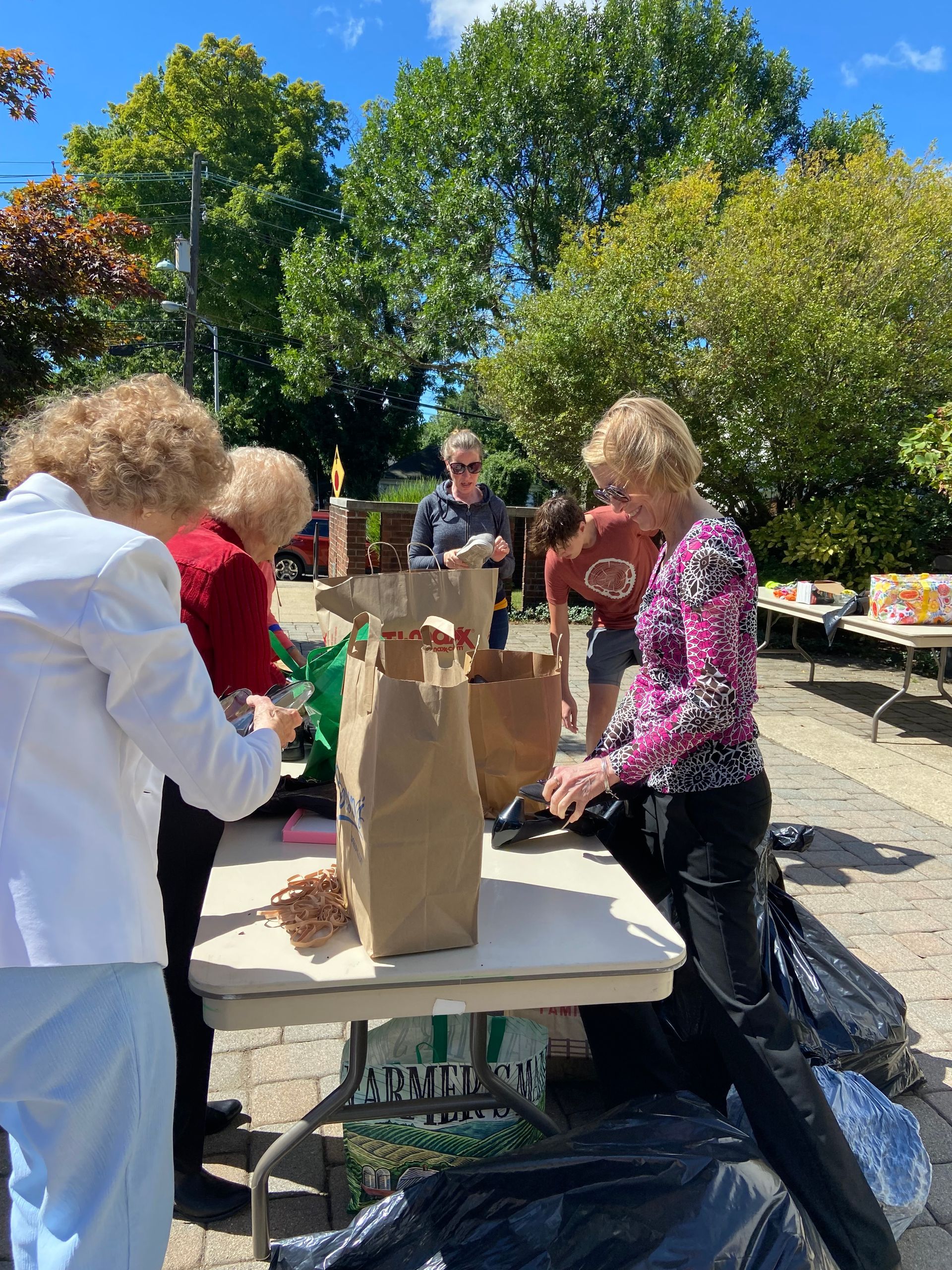 volunteers outside in the church courtyard assembling care packages for those in need on God's Work, Our Hands Sunday