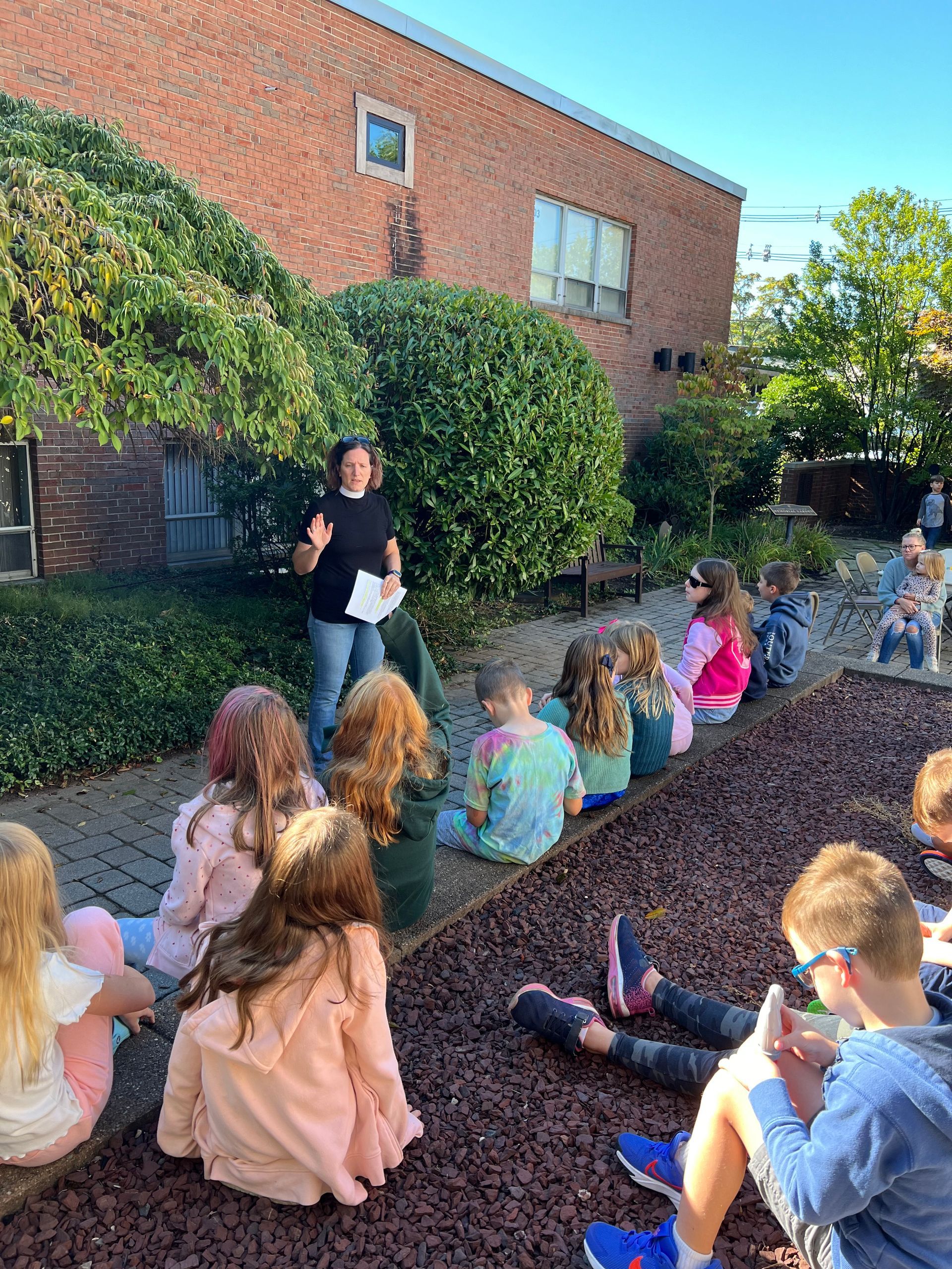 Pastor Irwin speaking to a group of children sitting outside in Calvary's courtyard.