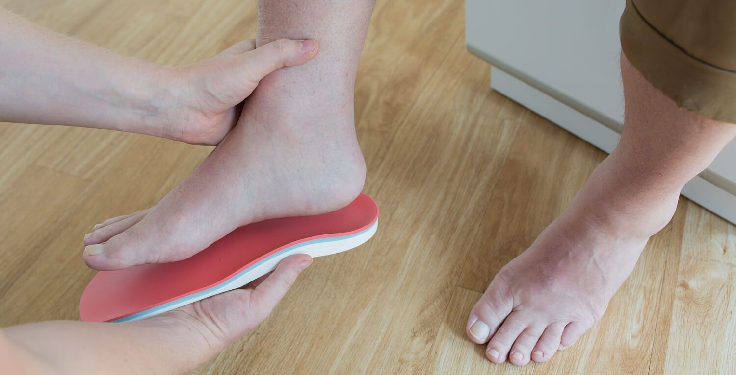 Foto einer Frau, die eine Einlage in ihren Schuh legt Foto einer Frau, die eine Einlage in ihren Schuh legt