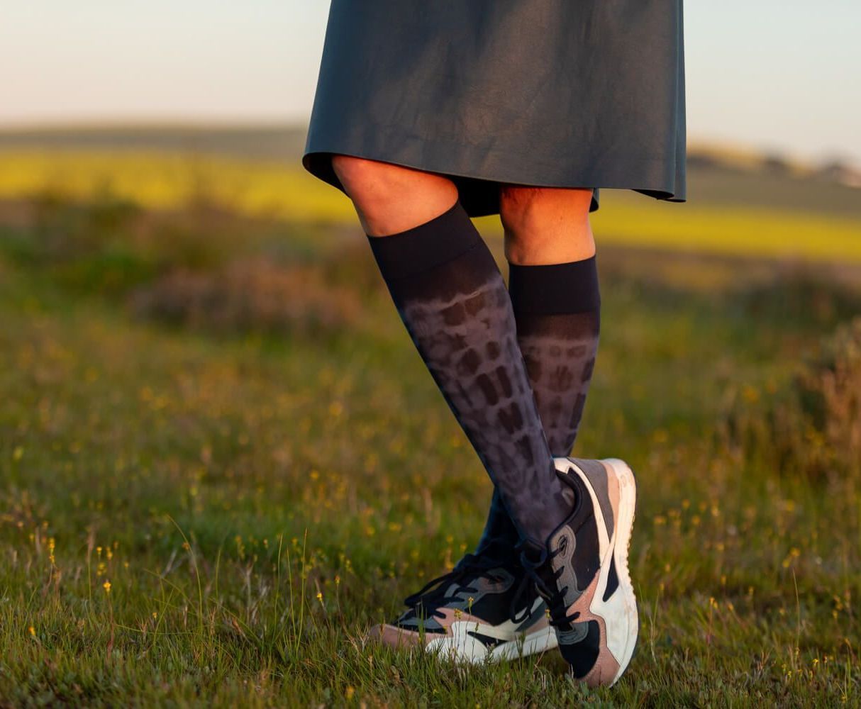 Foto von den Beinen eines Mannes und einer Frau, die mit Kompressionsstrümpfen einen Spaziergang machen
