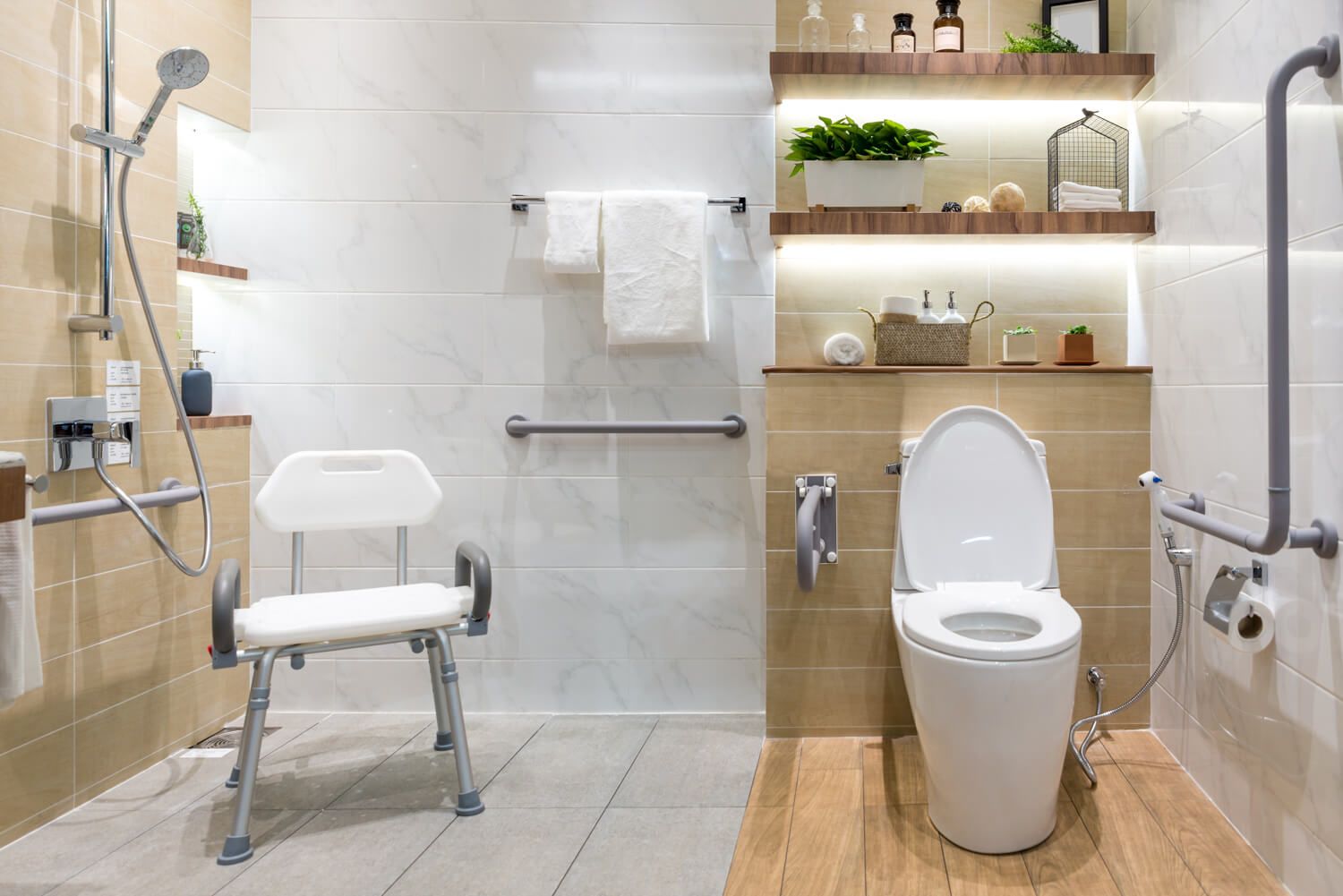 Foto eines Badezimmers mit diversen barrierefreien Elementen wie einer ebenerdigen Dusche, Griffen und Handläufen an den Wänden und einem Duschstuhl