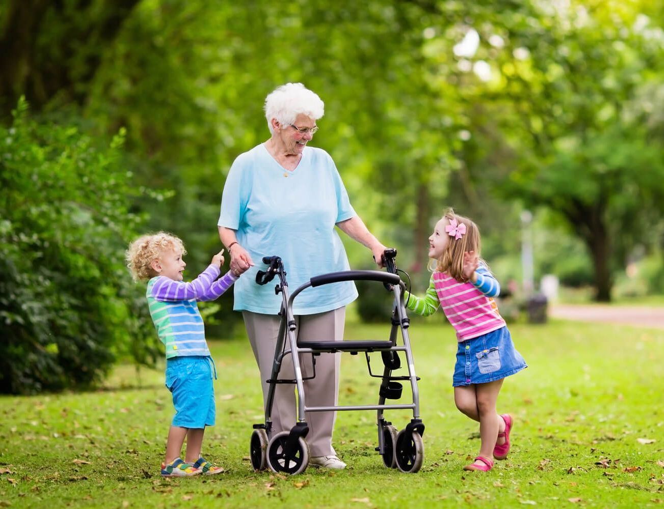 Foto einer älteren Frau an einem Rollator, die fröhlich mit zwei Kindern spielt